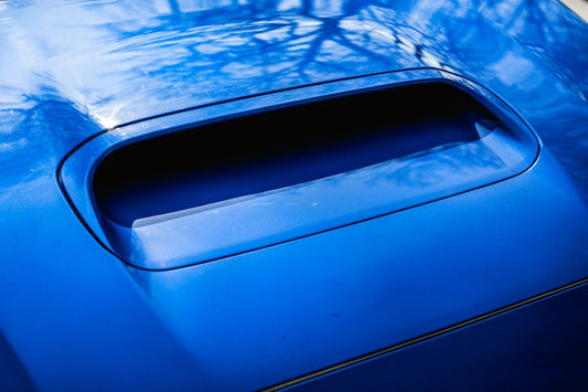Here is a possible caption: **blue car hood with an air scoop.**