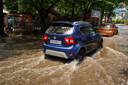 a blue car driving through a flooded street