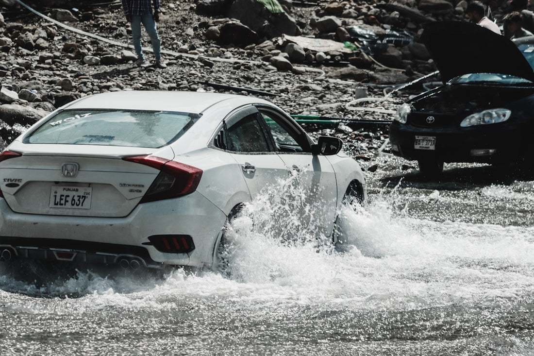 A white car driving through a flooded street