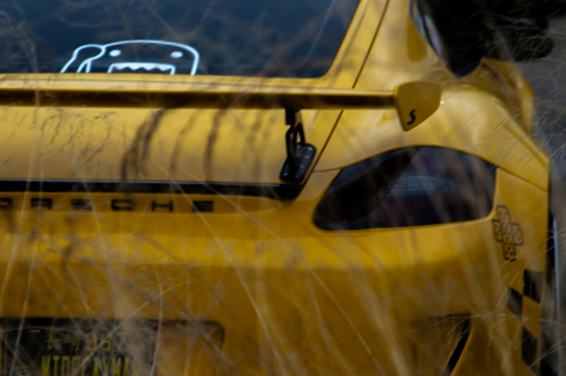 A close up of a yellow car with a sticker on it