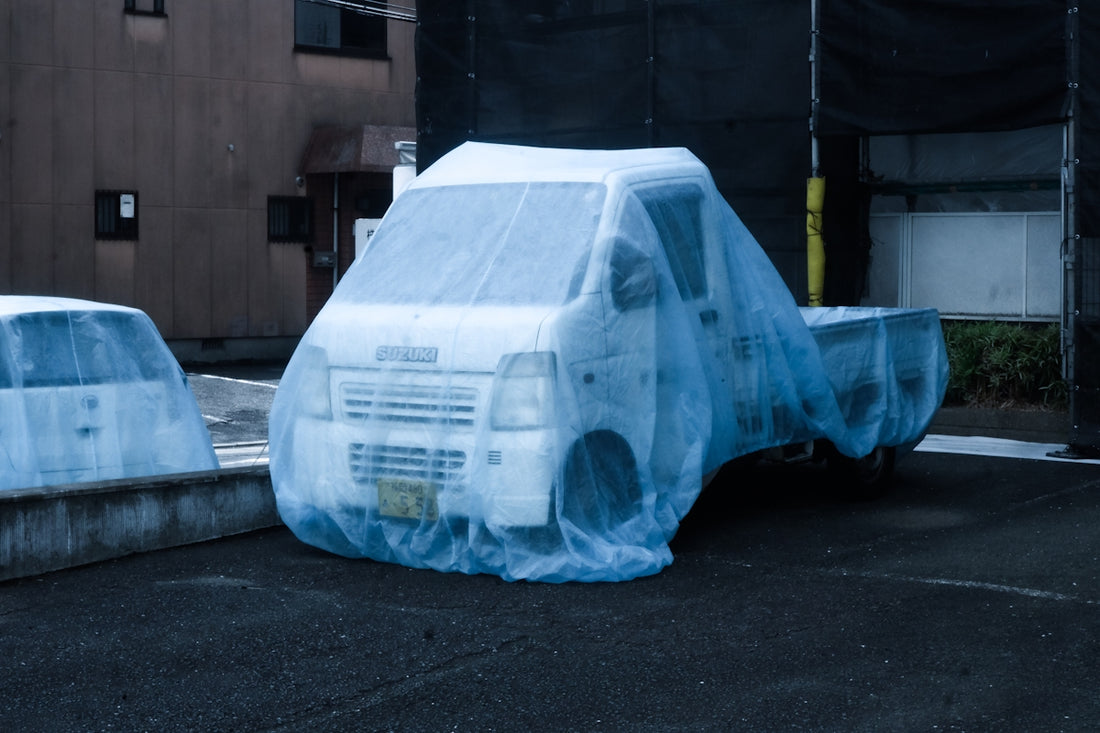 A car covered in plastic sitting in a parking lot